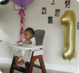 Photo of Celebration of Baby's first birthday. Baby sitting on High chair with cake